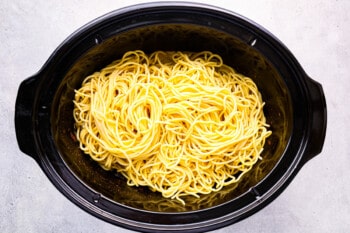a black crock pot filled with noodles.
