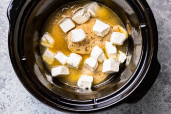 cream cheese cubes added to chicken in a crockpot.