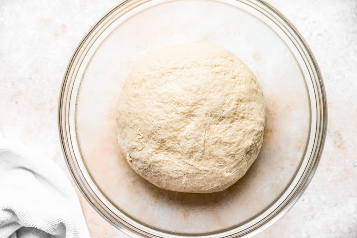 a dough ball in a glass bowl on a table.