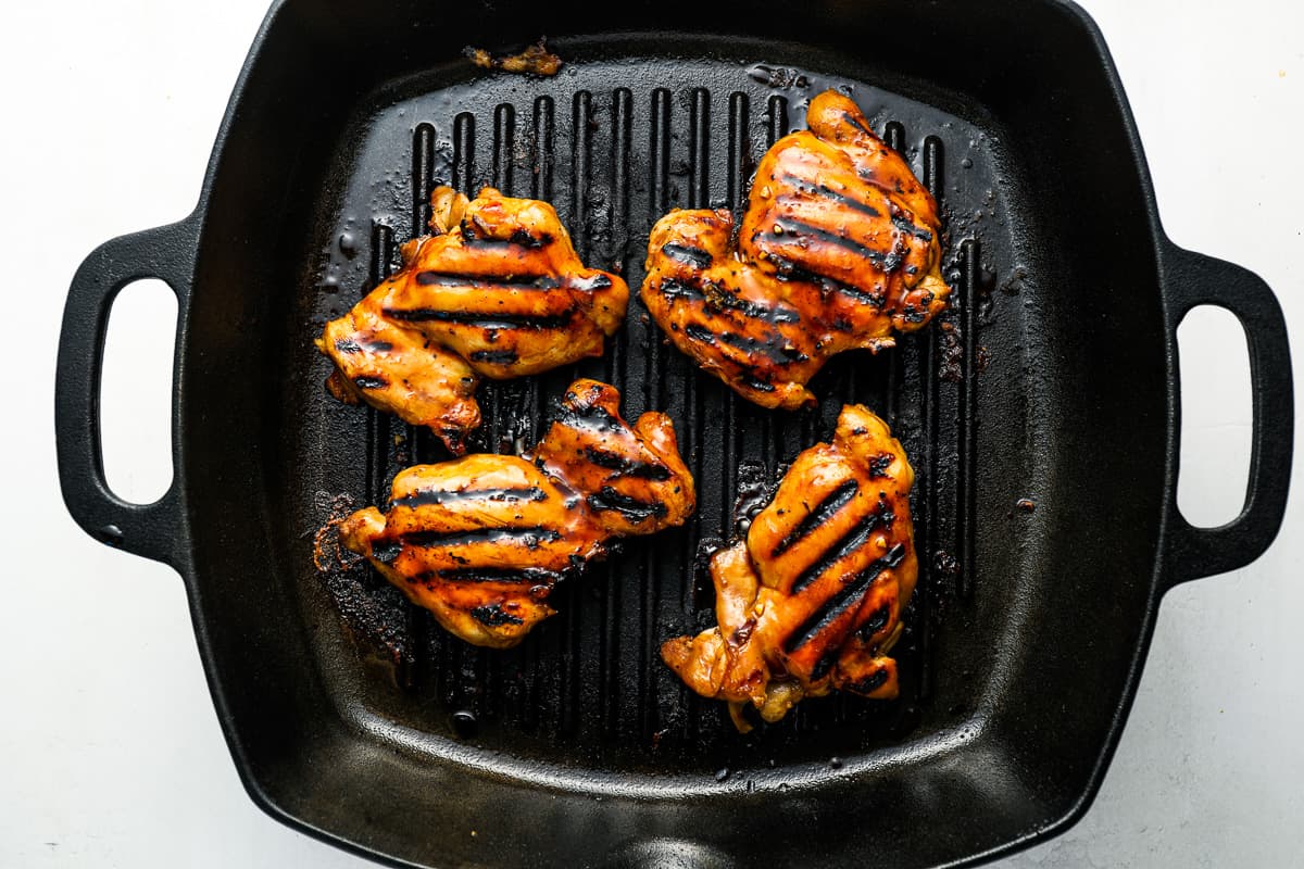 4 grilled chicken thighs in a grill pan.
