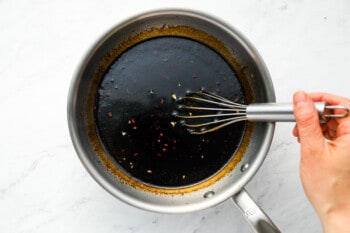 korean bbq sauce thickened with cornstarch in a saucepan with a whisk.