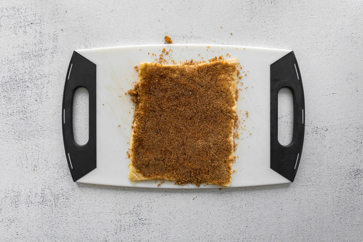 cinnamon filling spread over crescent dough on a plastic cutting board.