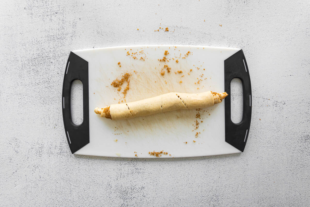 a mini cinnamon roll log on a plastic cutting board.