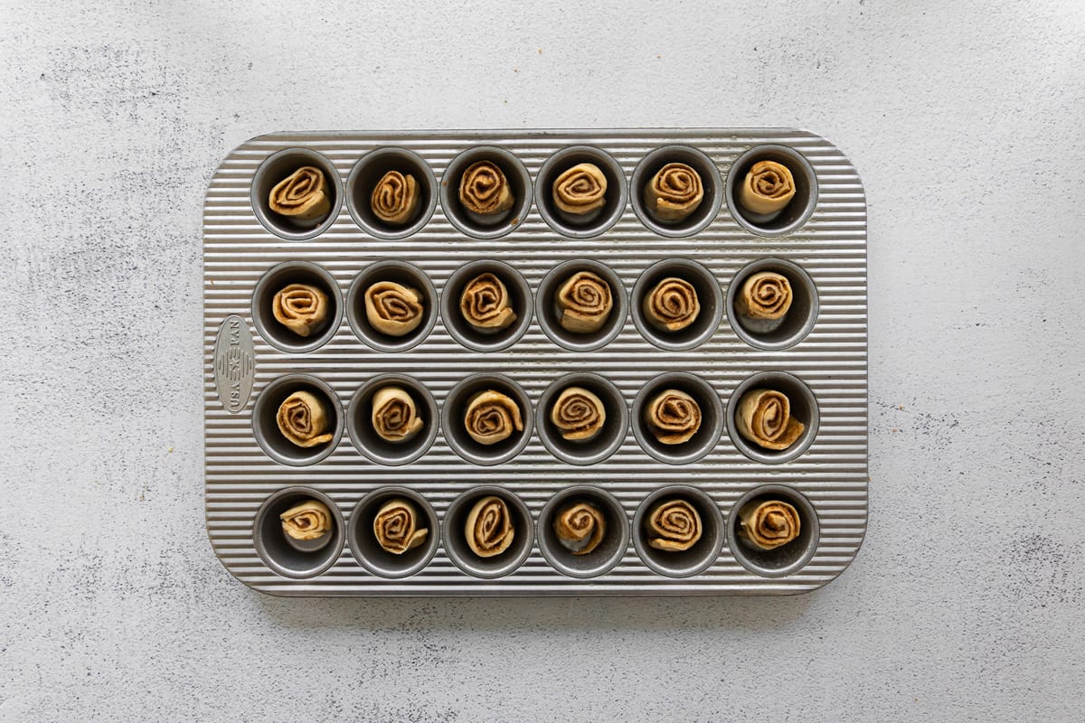 mini cinnamon rolls in the wells of a mini cupcake tin.