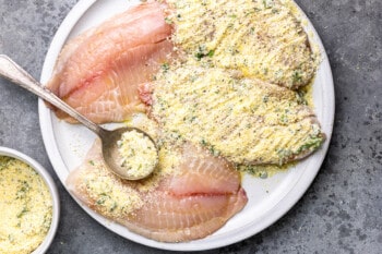 overhead view of tilapia filets being coated in a parmesan crust.