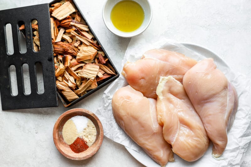 chicken breasts on a plate with spices and a frying pan.