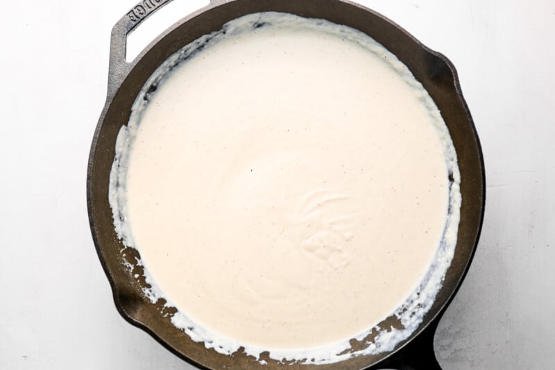 cream cheese added to thickened half-and-half in a cast iron pan.