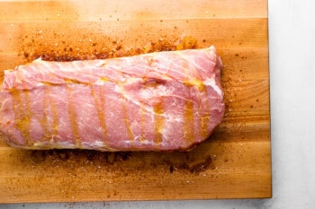 a trimmed raw pork loin roast on a cutting board drizzled in olive oil.