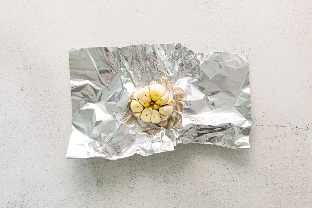 a head of garlic surrounded by aluminum foil.