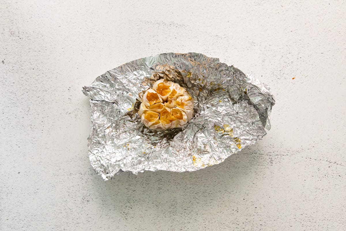 a roasted head of garlic surrounded by aluminum foil.