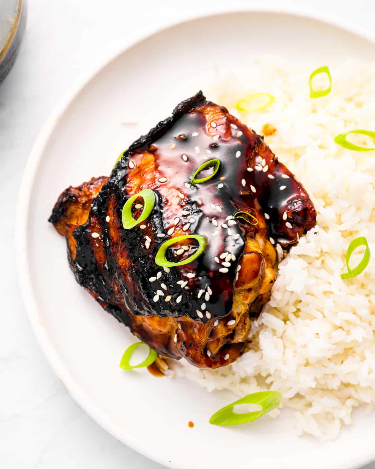 a piece of grilled korean bbq chicken on a white plate with rice.