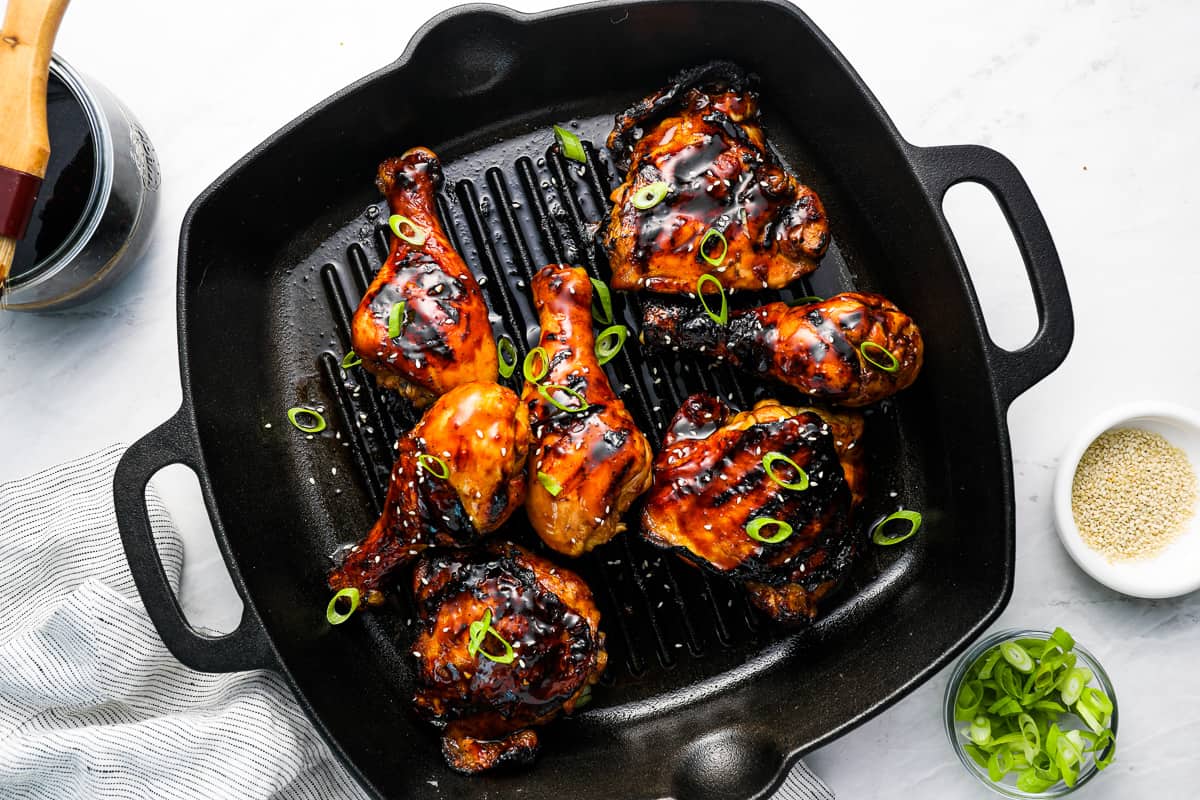 overhead view of korean bbq chicken thighs and drumsticks in a grill pan.