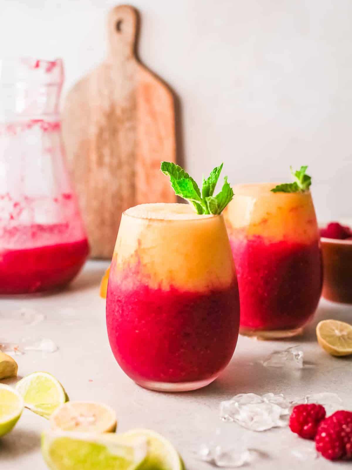 two glasses with layered raspberry mango daiquiris