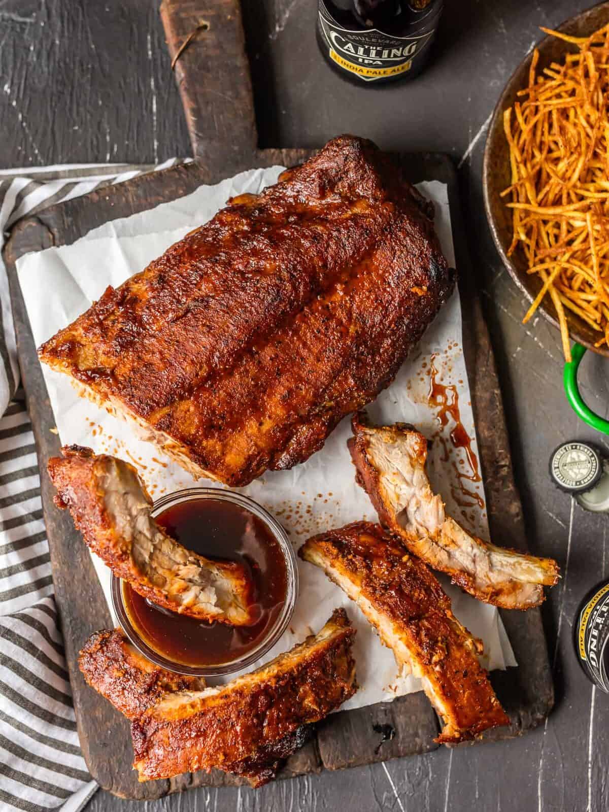 OVEN BAKED RIBS are just sooo tasty. I like cooking ribs in the oven because it's super easy and they turn out so moist. They're also great for rainy days when you don't have access to your grill. These dry rubbed ribs are one of our favorite easy dinners for summer. So kick your BBQ skills up a notch with these Easy Oven Baked Ribs, whether you're making spare ribs or baby back ribs! Either way, you're left with SO MUCH FLAVOR! Oven Baked Ribs on a wood platter
