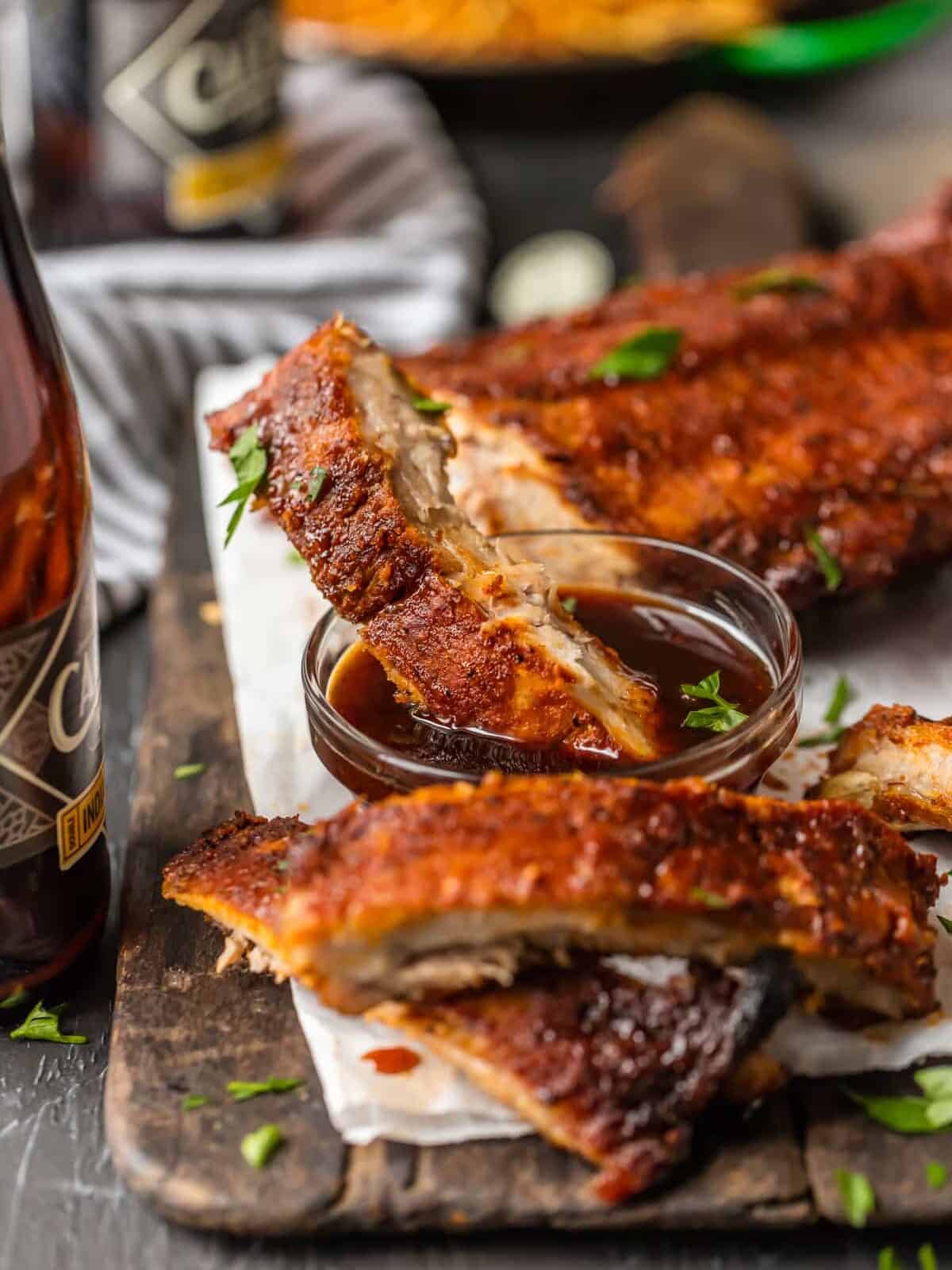 OVEN BAKED RIBS are just sooo tasty. I like cooking ribs in the oven because it's super easy and they turn out so moist. They're also great for rainy days when you don't have access to your grill. These dry rubbed ribs are one of our favorite easy dinners for summer. So kick your BBQ skills up a notch with these Easy Oven Baked Ribs, whether you're making spare ribs or baby back ribs! Either way, you're left with SO MUCH FLAVOR! A single rib dipped in a bowl of bbq sauce
