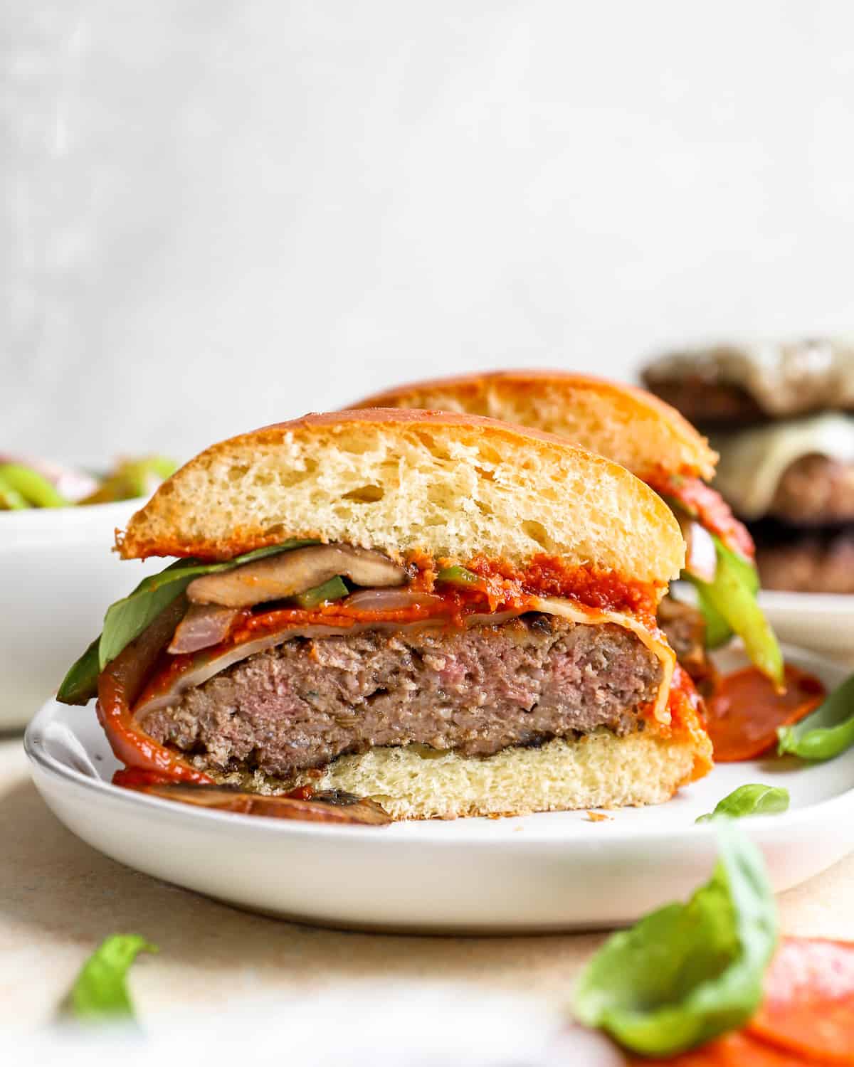 a beef and Italian sausage burger cut in half on a plate.