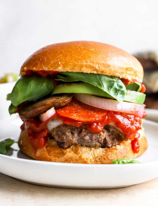 a burger on a plate with tomatoes, lettuce, and other toppings.