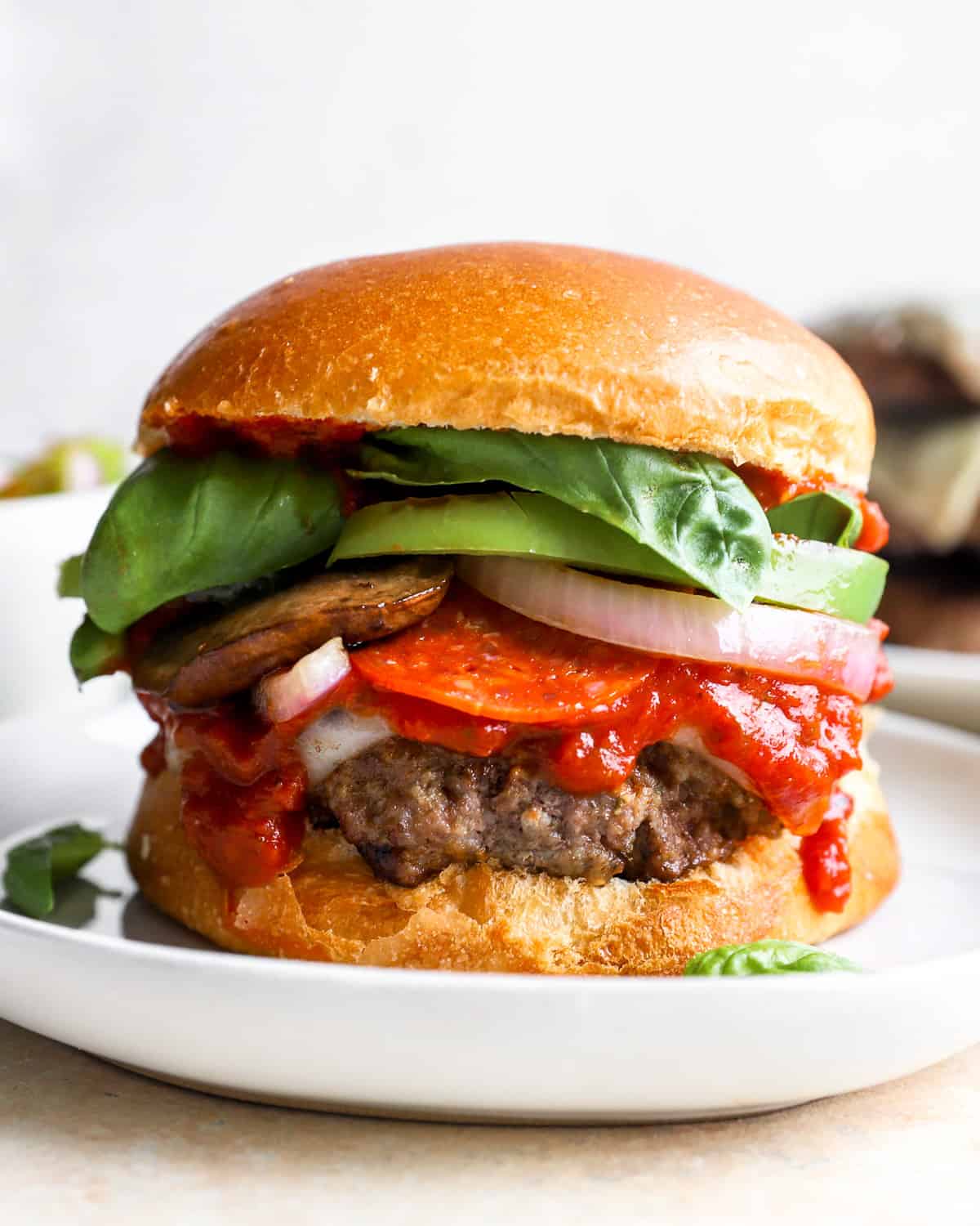 a pizza burger on a plate with tomatoes, lettuce, and other toppings.
