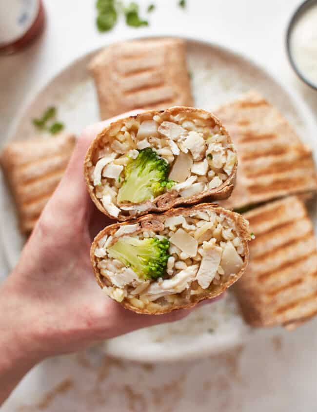a hand holding stacked chicken ranch wrap halves to show the filling.