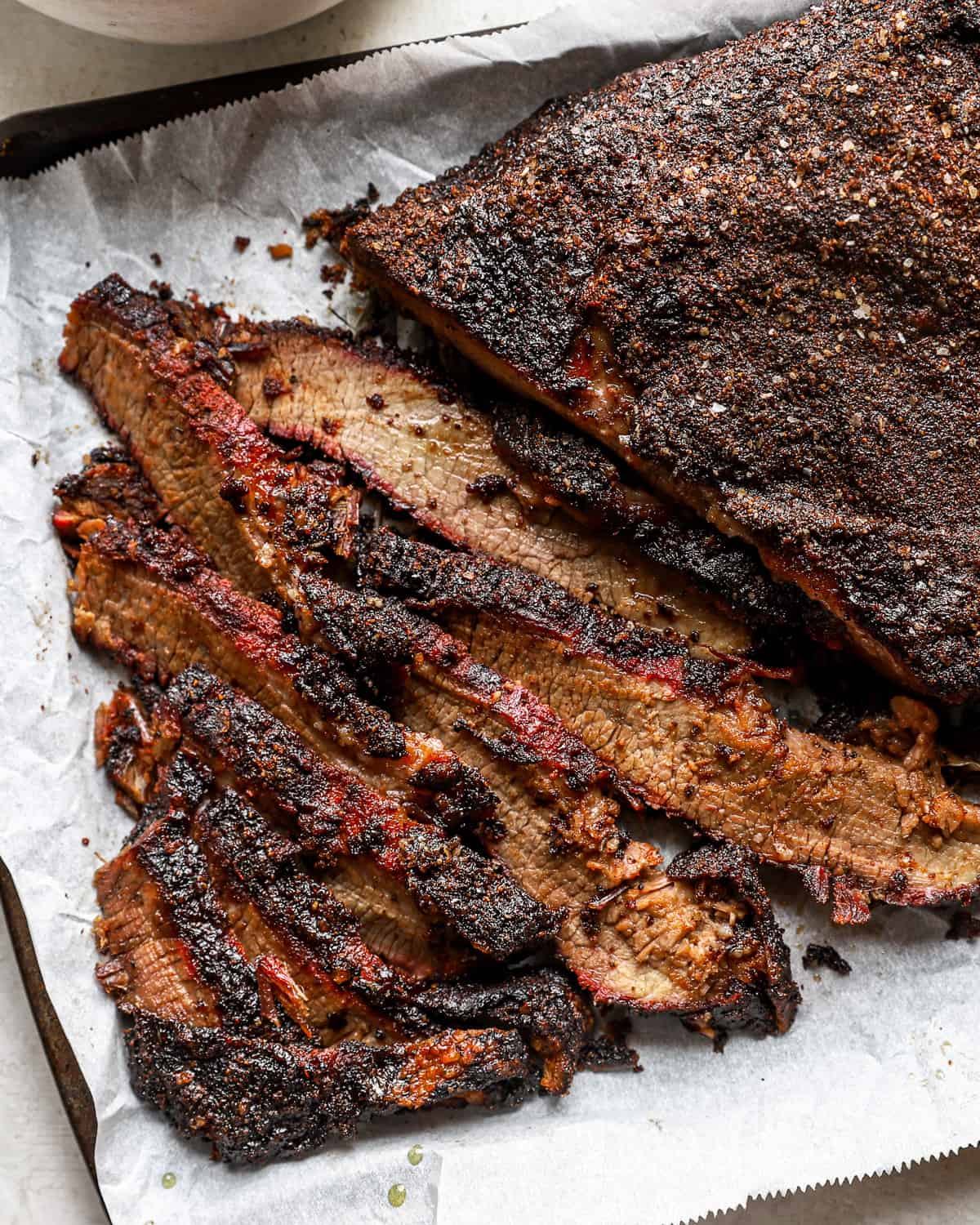 close up on smoked beef brisket, partially cut into slices.