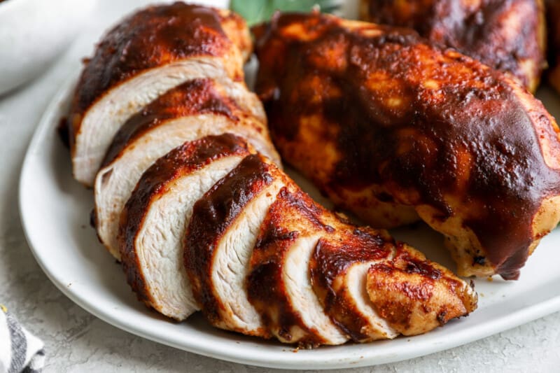 sliced bbq chicken on a white plate.