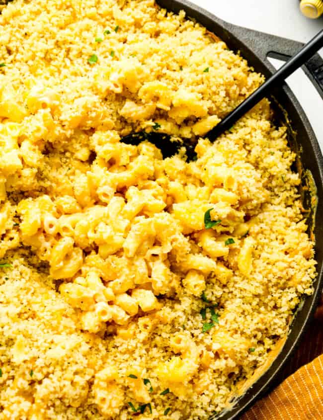 close up overhead view of smoked mac and cheese in a cast iron skillet with a serving spoon.