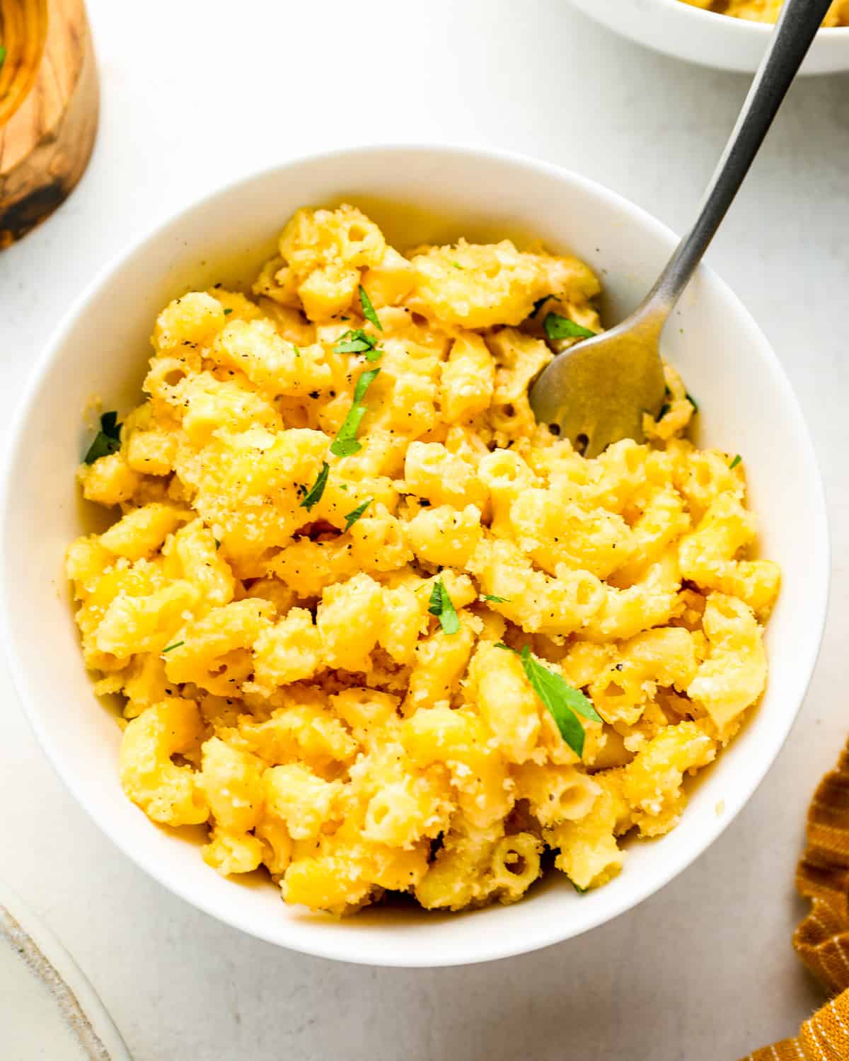 overhead view of a serving of smoked mac and cheese in a white bowl with a fork.