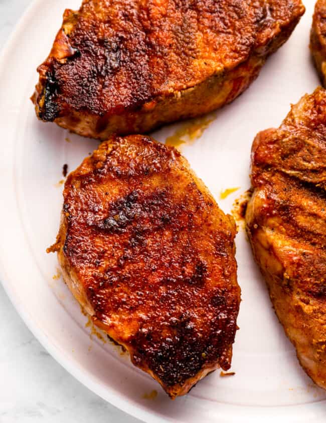 close-up overhead view of smoked pork chops on a white plate.