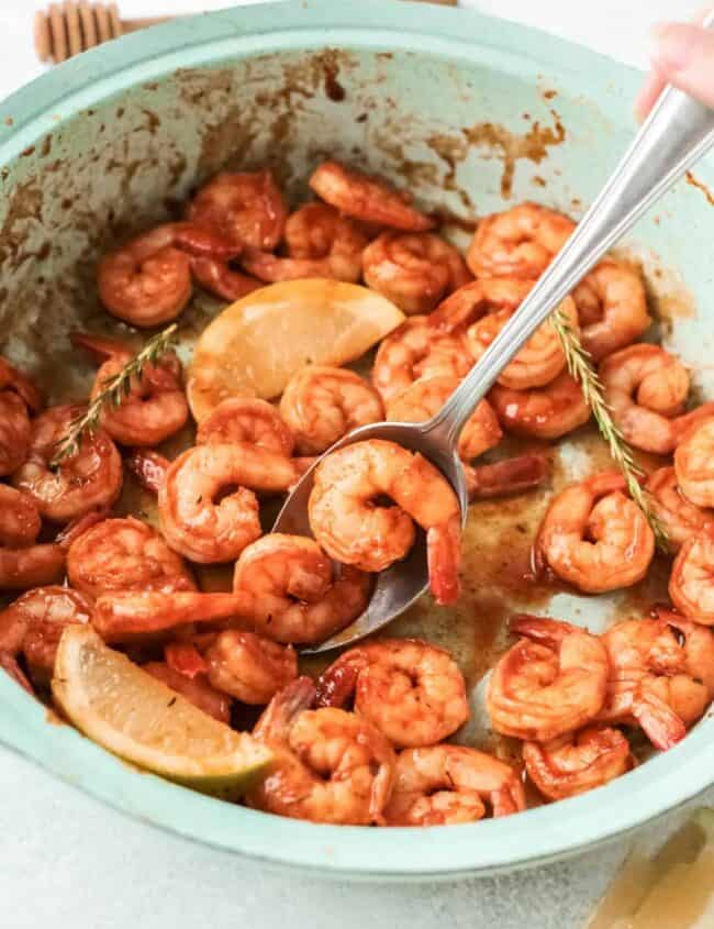 a spoon scooping a spicy mexican shrimp from a blue bowl.