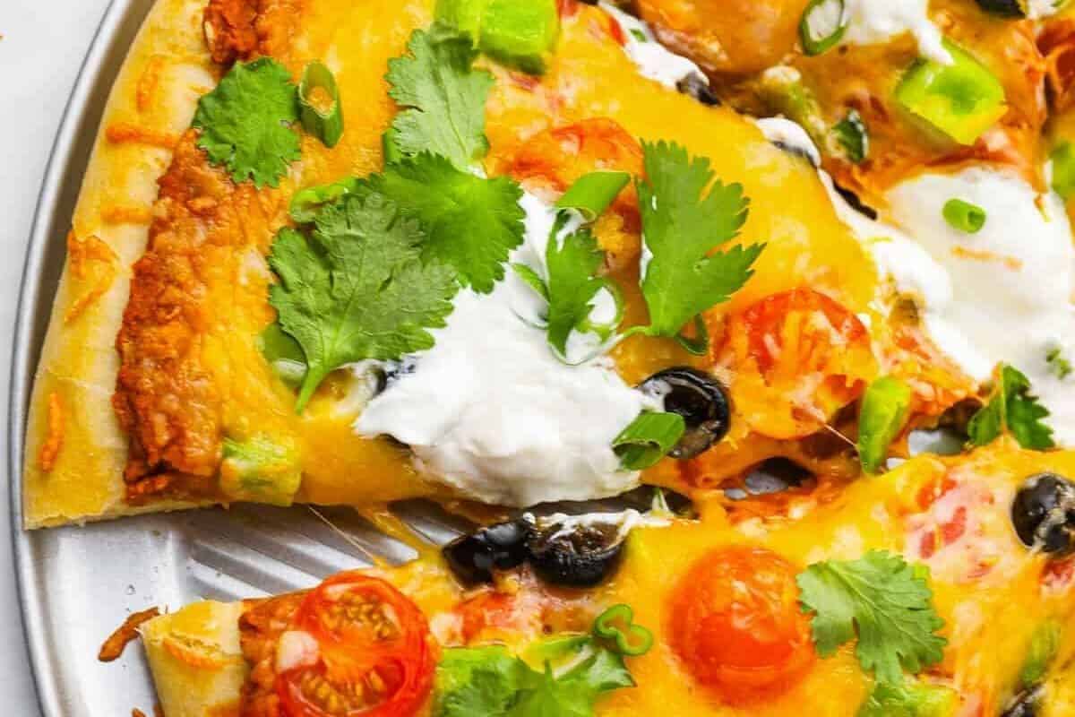 Taco pizza with sour cream, green onions, and cilantro.