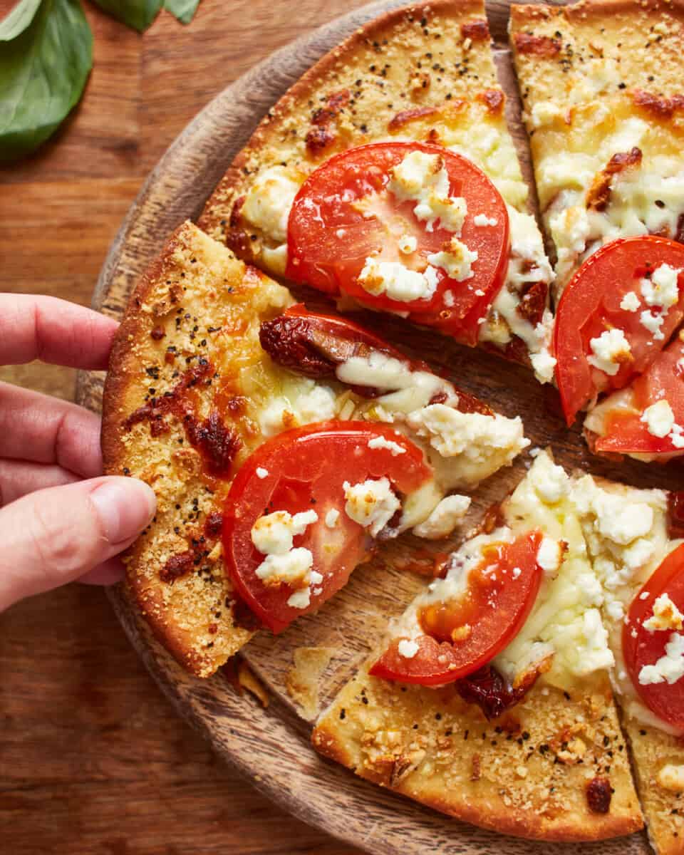 overhead view of a hand removing a slice of white pizza from a pie.