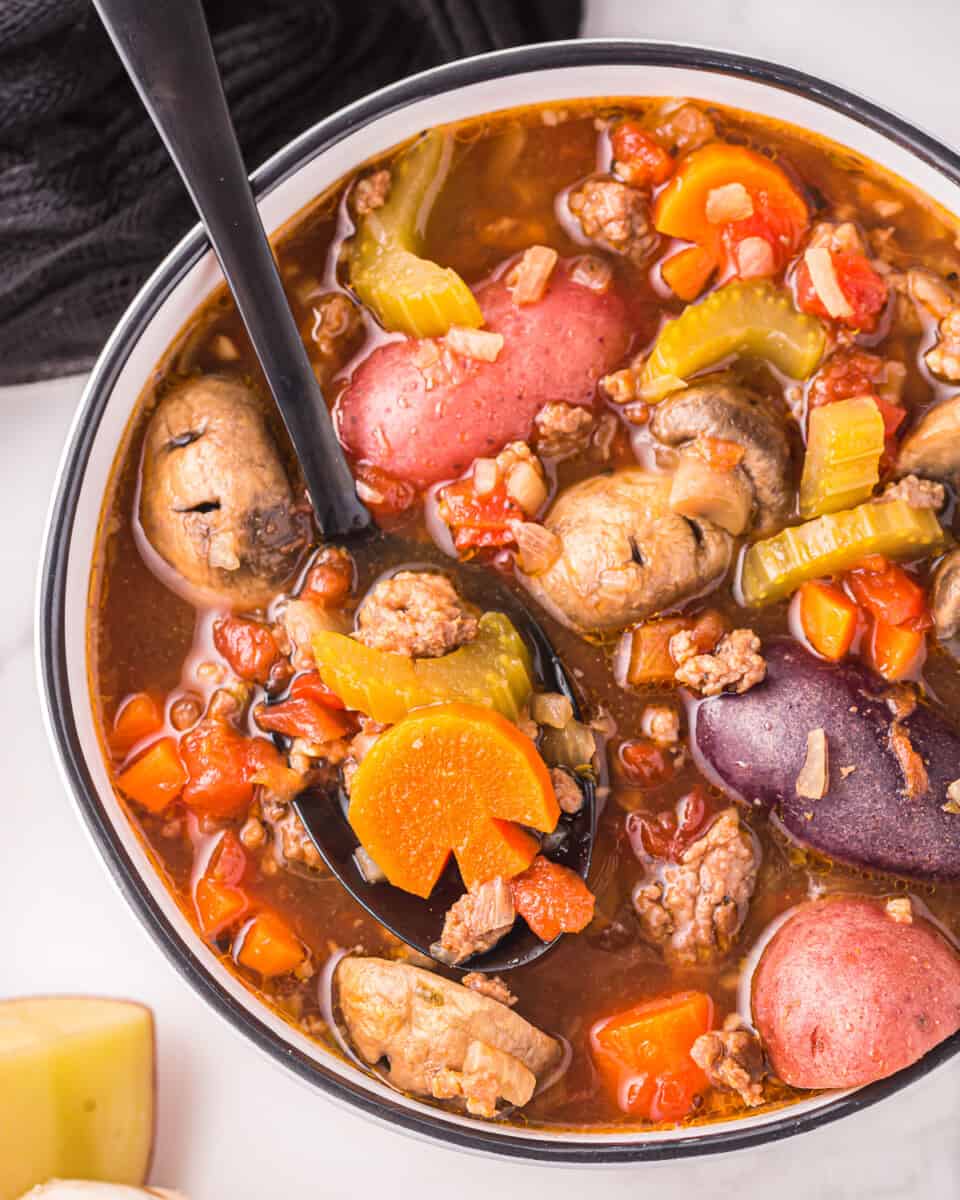 a bowl of soup with meat, vegetables and potatoes.