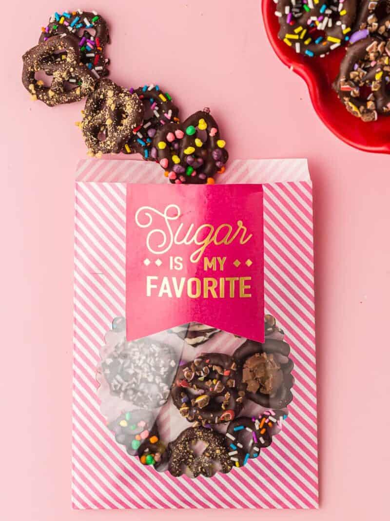 chocolate covered pretzels in a pink and white striped treat bag