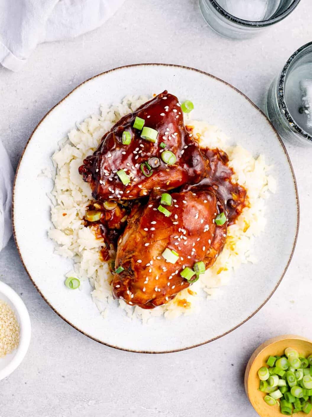 overhead image of honey garlic chicken on top of rice on a white plate