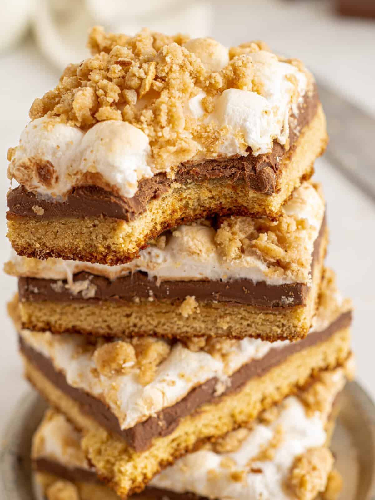a bitten smores bar stacked on top of 3 more bars on a small gray plate.