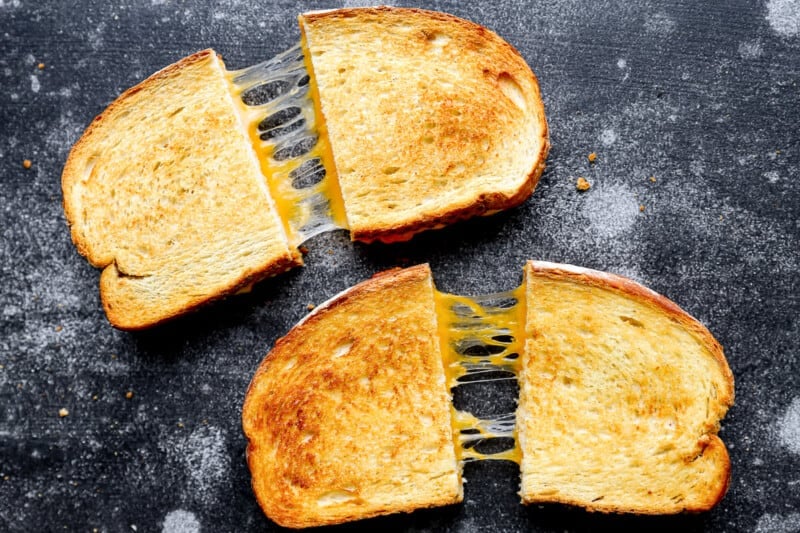 overhead view of 2 air fryer grilled cheese sandwiches sliced down the middle and pulled apart to show the cheese pull.