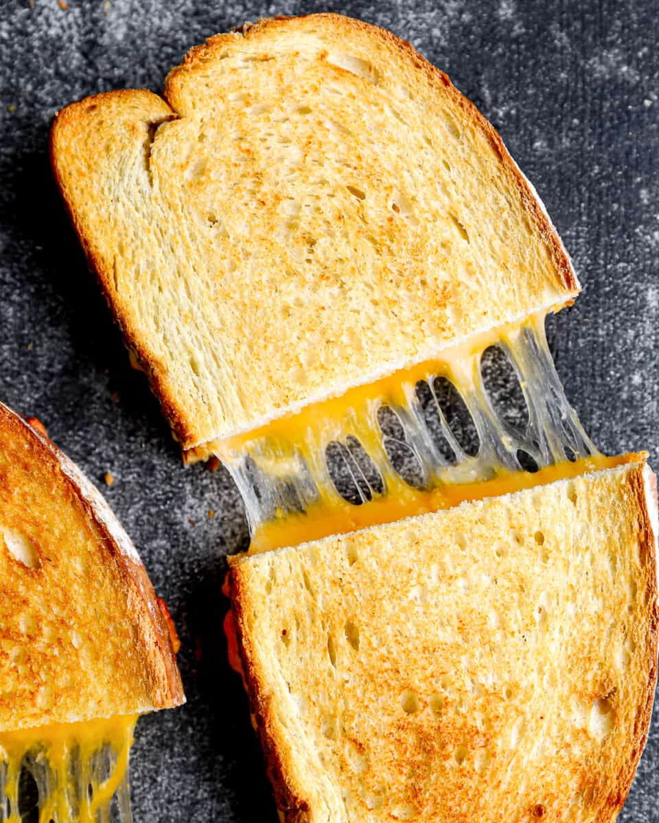 close up overhead view of an air fryer grilled cheese sandwich halved and pulled apart to show the gooey cheese.