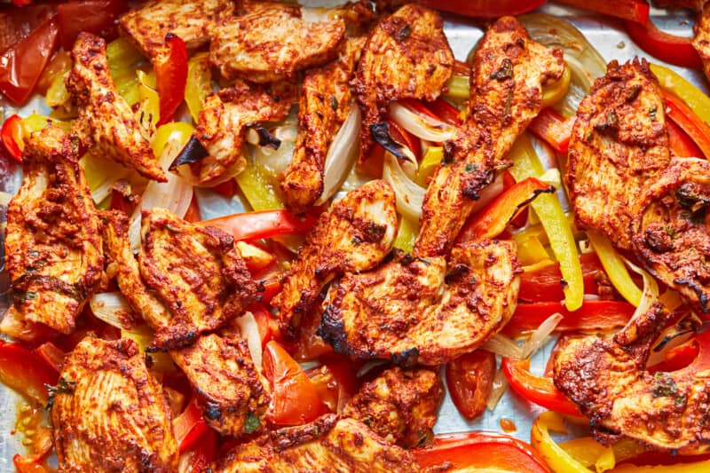 grilled chicken with peppers and onions on a baking sheet.