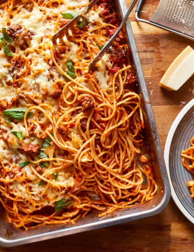 a dish of spaghetti and meatballs on a wooden table.