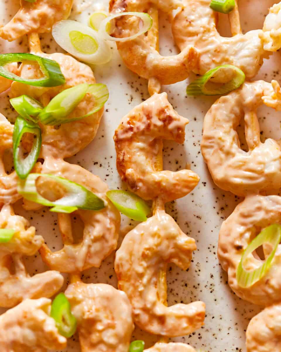 shrimp skewers on a baking sheet with green onions.