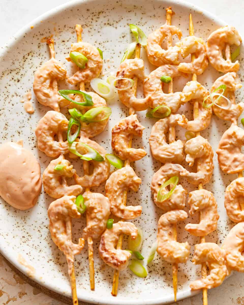 shrimp skewers with dipping sauce on a plate.