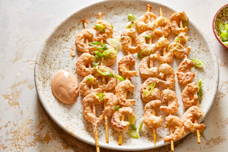 shrimp skewers on a plate with dipping sauce.