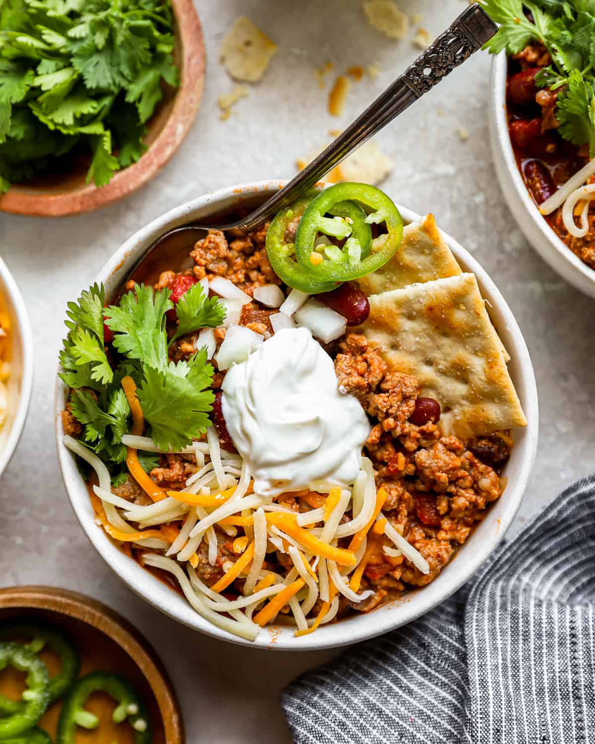 a bowl of chili with sour cream and tortilla chips.