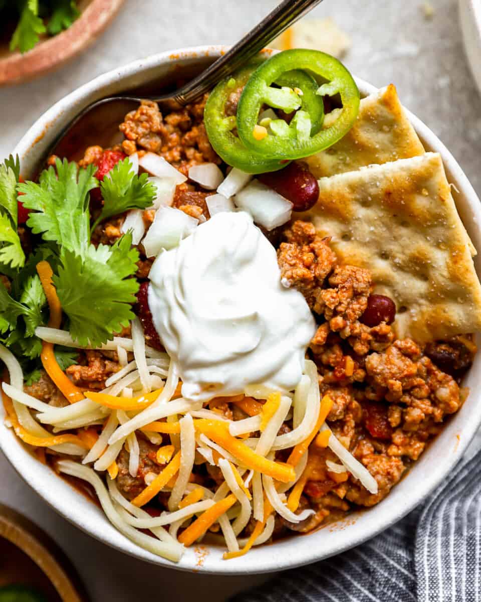 a bowl of chili with sour cream and tortilla chips.