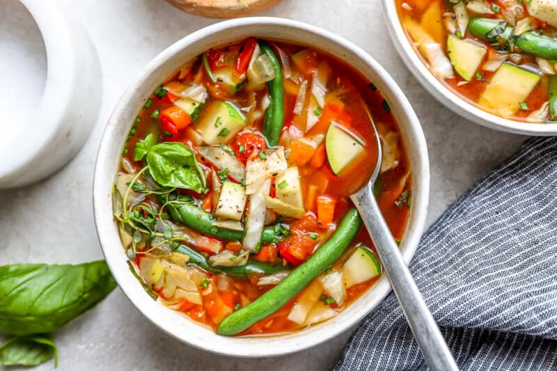 a serving of cabbage soup in a white bowl with a spoon.