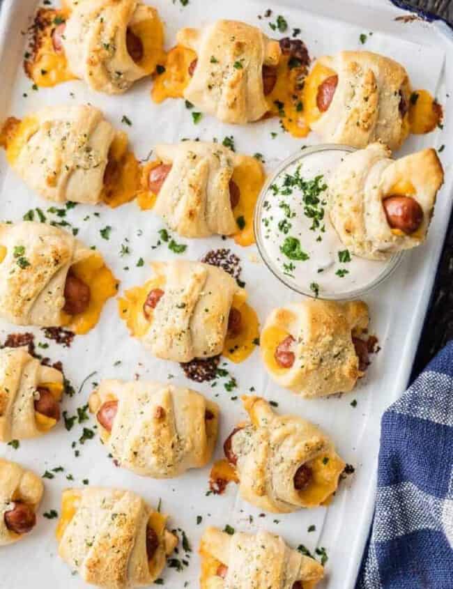 Pigs in a blanket with cheese on a baking sheet.