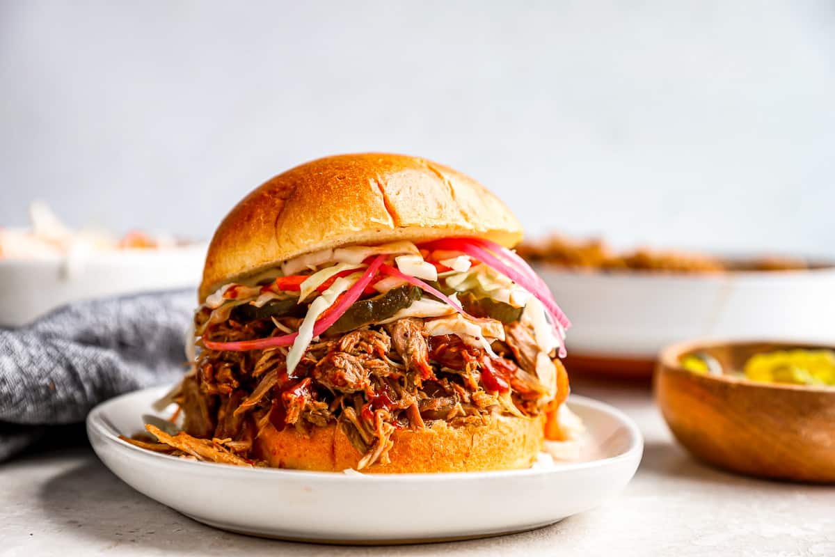 a pulled pork sandwich on a white plate.