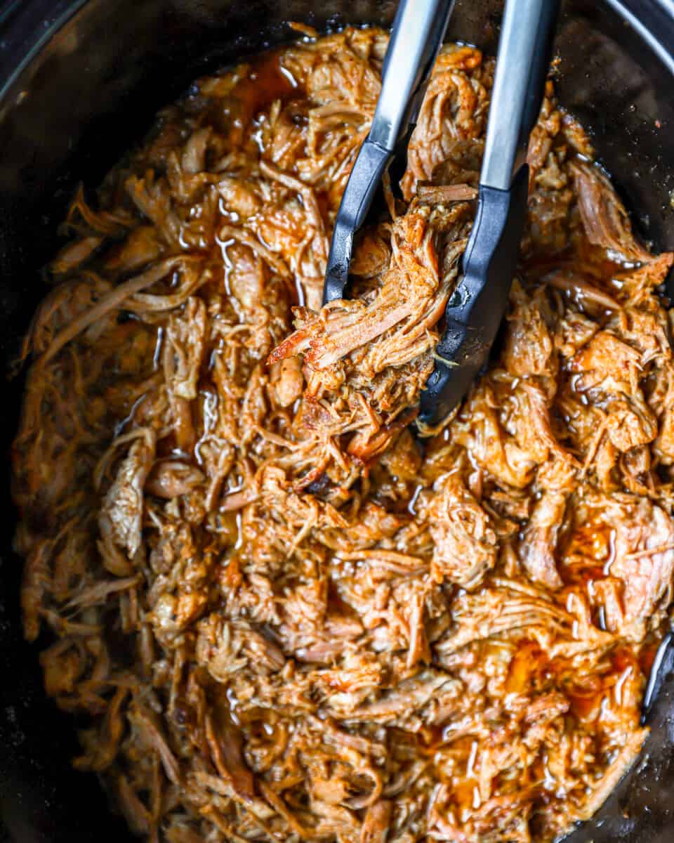 pulled pork in a slow cooker with two forks.