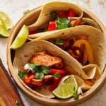 chicken tacos in a wooden bowl with peppers and lime.