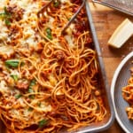 a dish of spaghetti and meatballs on a wooden table.